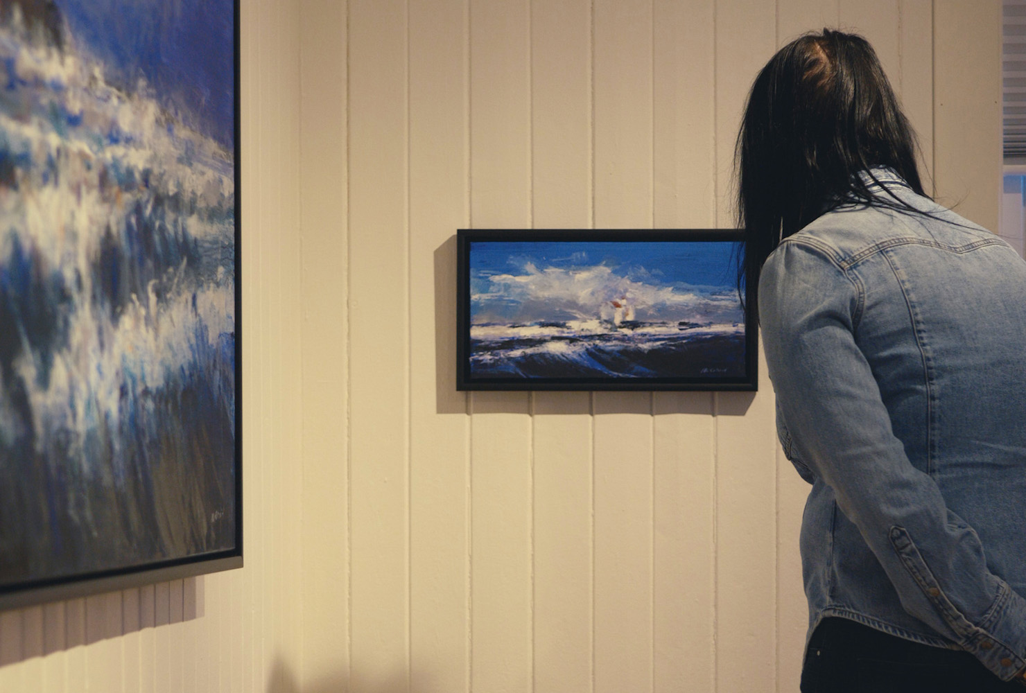 A woman taking a look at artwork in Galleri Lofoten